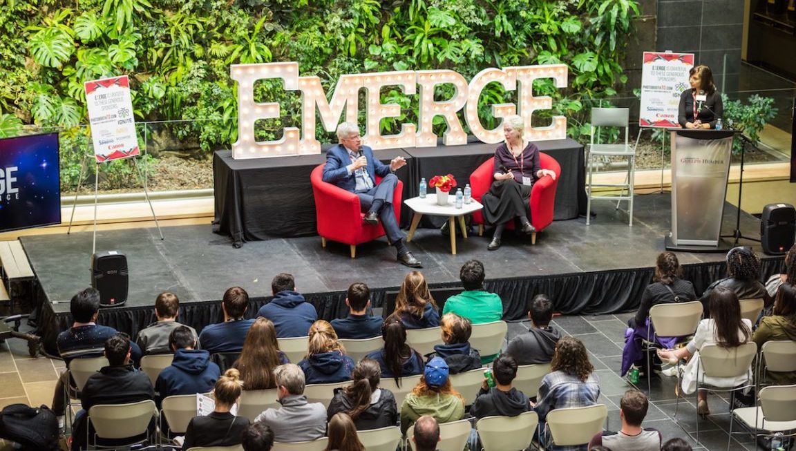 Man and woman speaking on stage as a crowd listens at the Emerge 2017 conference