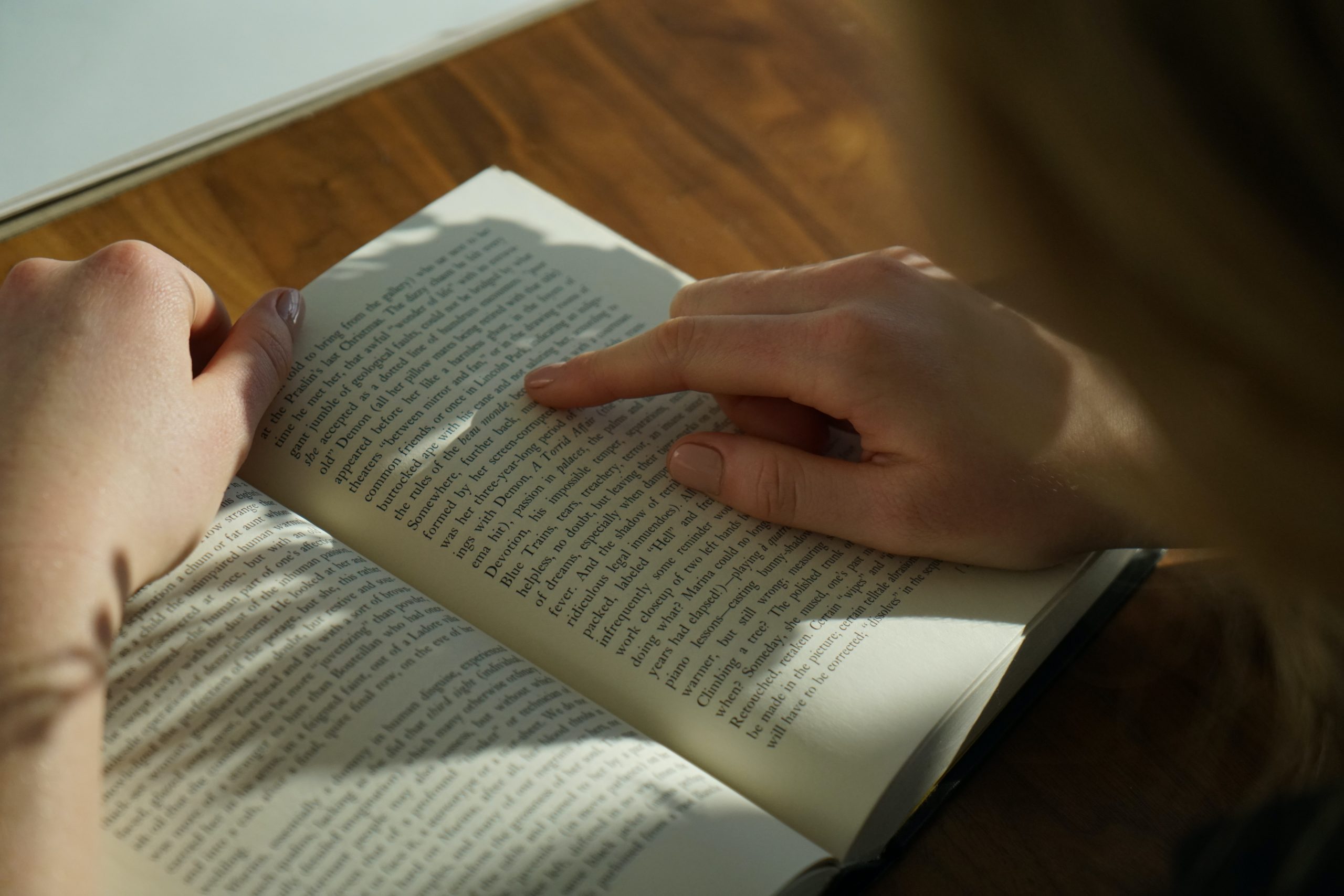 Closeup of a person reading and pointing at a page of a book